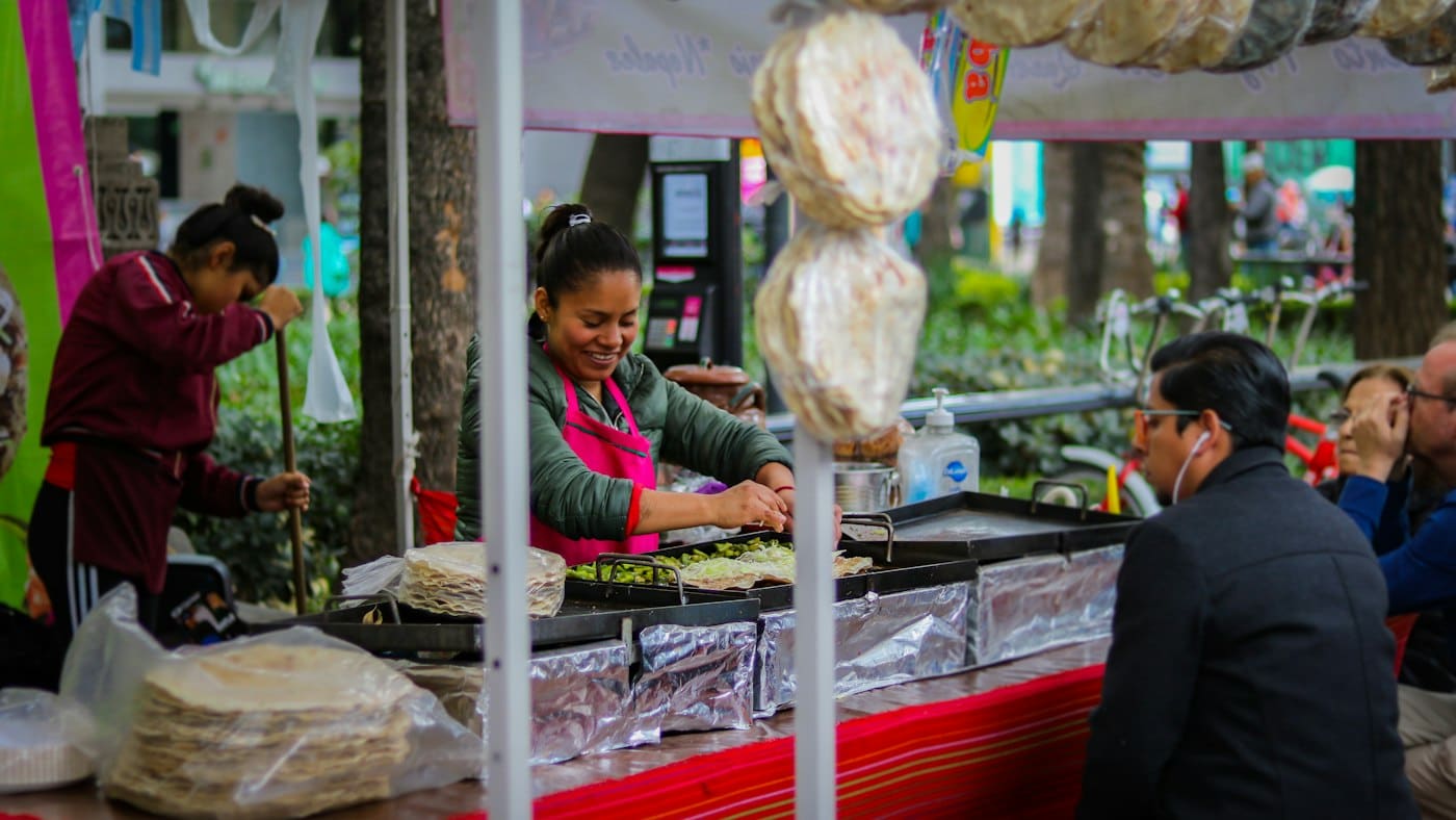 Cocinera entregándole el pedido a un cliente en su puesto de comida